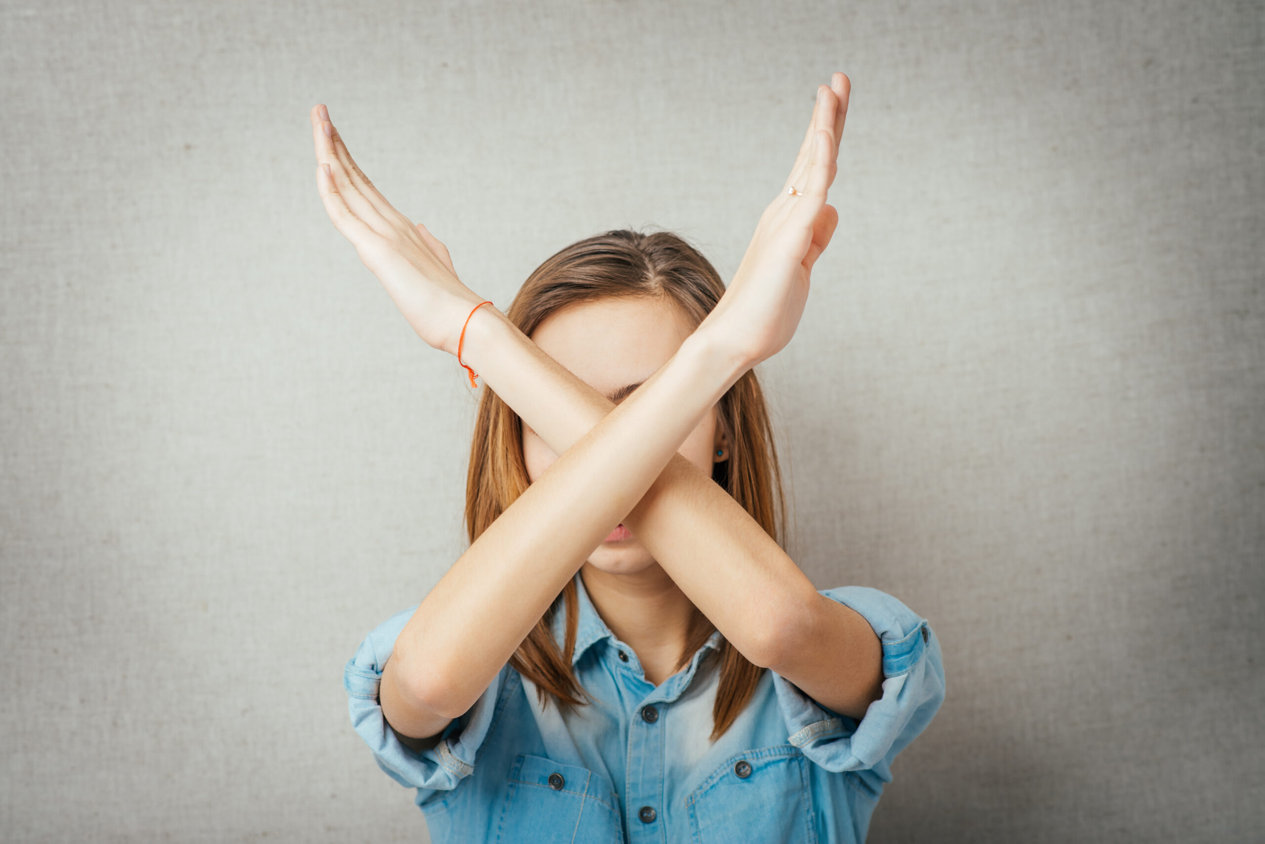 Woman crossing her arms over her face telling What Not to Do on Social Media