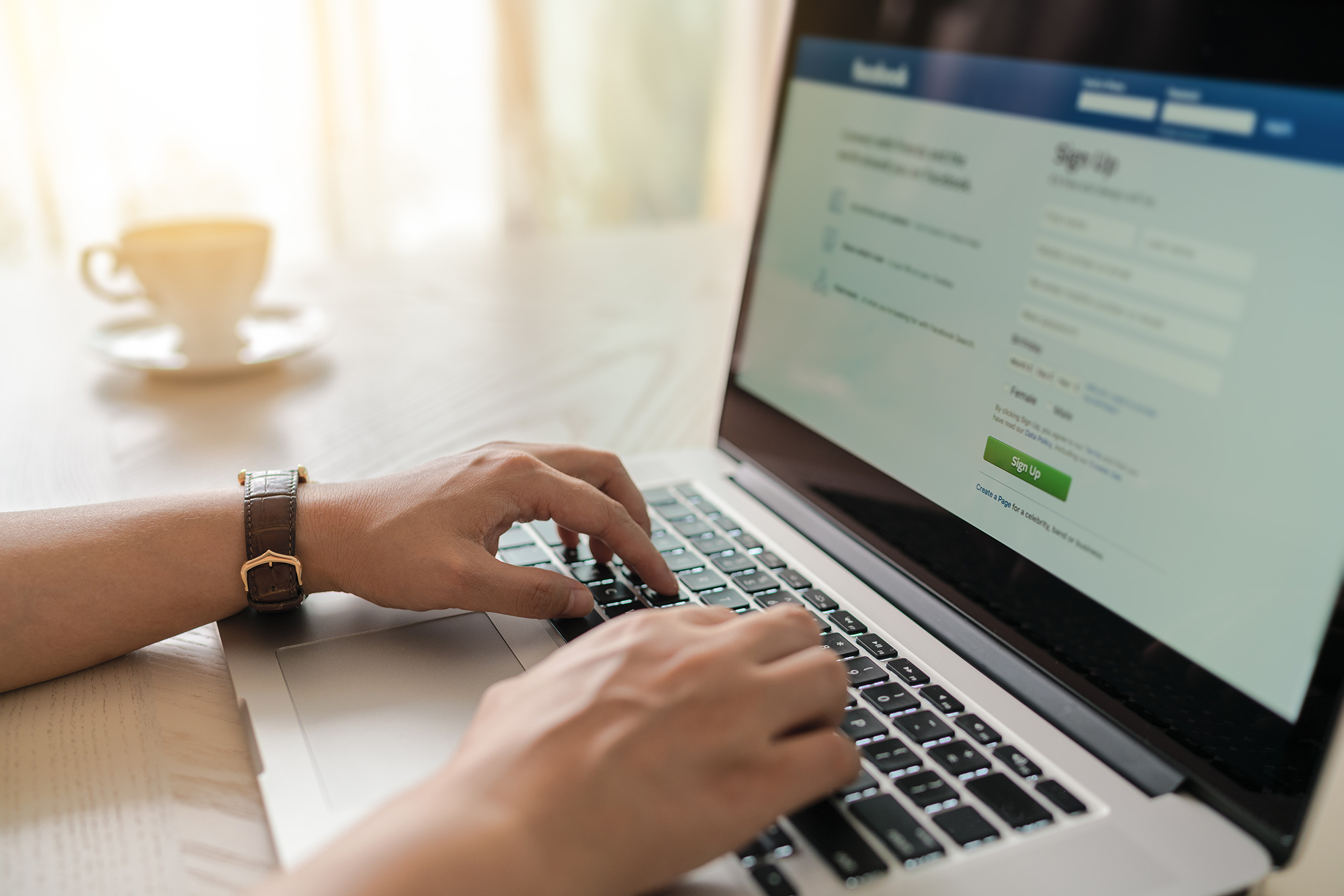 Someone typing on a laptop displaying the Facebook login page, highlighting concerns around social media oversharing.