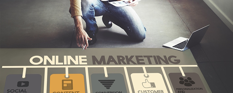 Person kneeling next to a laptop showing online marketing graphic, representing healthcare online marketing.