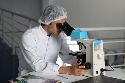 Person in a lab coat using a microscope in a laboratory setting, illustrating a marketing plan for cardiology.