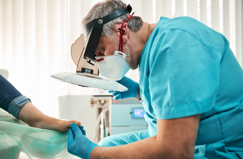A podiatrist and a patient having his foot examined for podiatry marketing ideas.