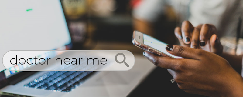 A person holding a phone and searching for "doctor near me," symbolizing SEO for doctors.